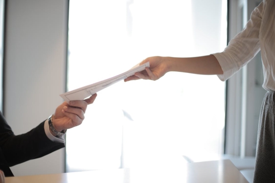 A person giving a stack of papers