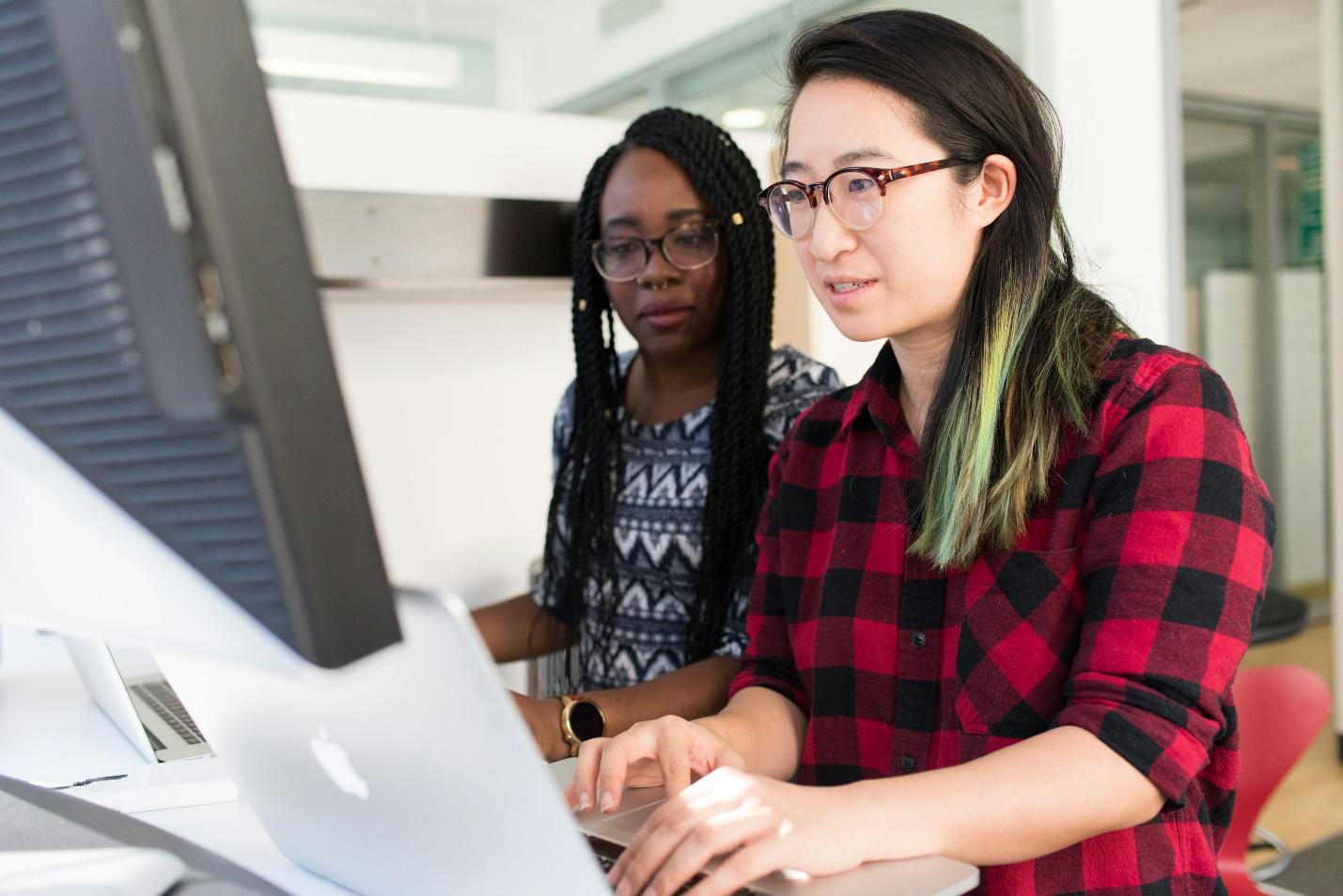 Two employees from different ethnic backgrounds working on a PC together