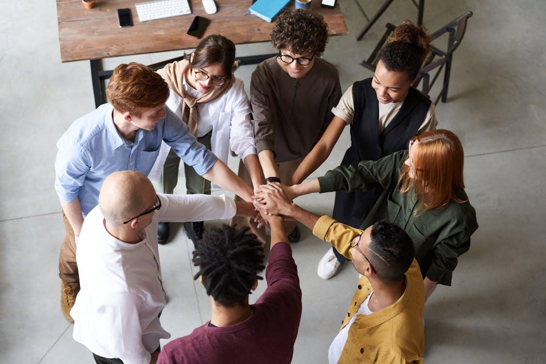 A diverse employee team of an IT company holding each others’ hands