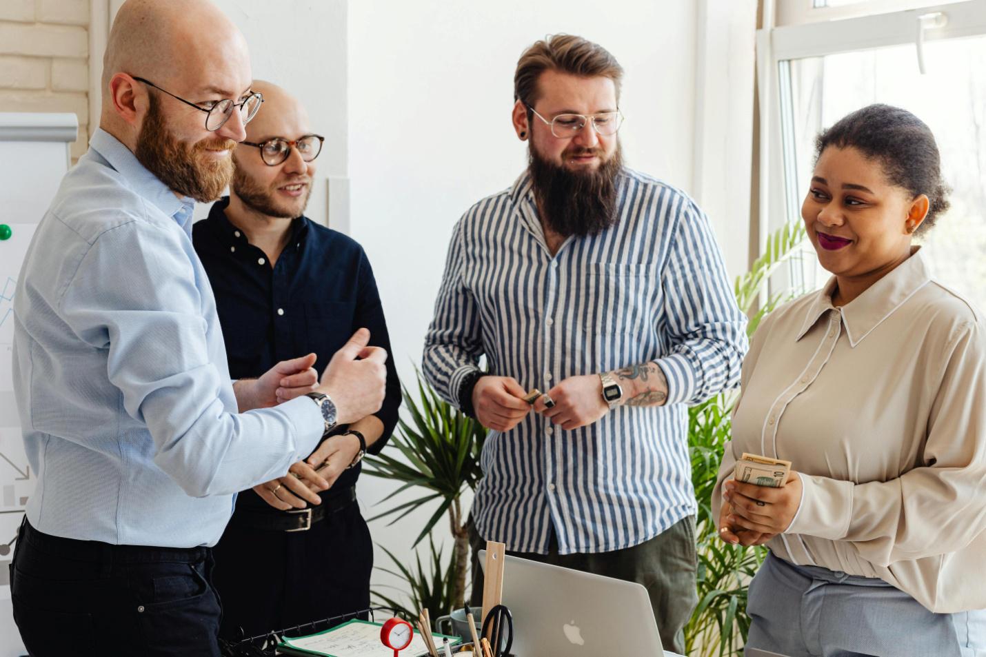 A picture of three male employees with a female employee holding cash