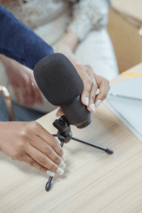 Adjusting a microphone on a small stand during a podcast recording session.